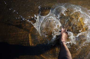 Adamın yalın ayak yağmurdan sonra boş yoldaki cam su birikintisine atlıyor. Kristal berrak su yüksek hızlı kepenk ve seçici odak ile sıçrar.