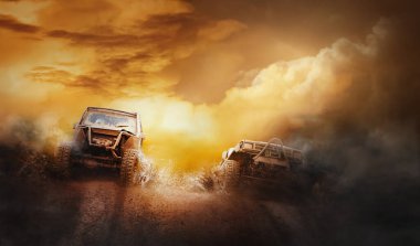 Off-road yarışmasında çamur çukurundan çıkan iki off-road aracı.