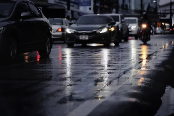 Blurry cars in a long queue on the busy city street during hard rain fall at night.Selective focus and shallow depth of field composition.