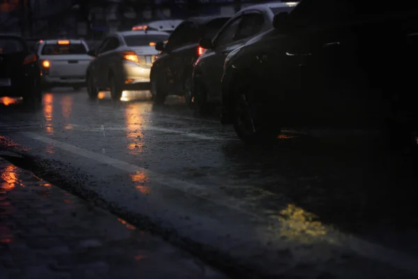 激しい雨の夜に忙しい街の通りに長蛇の列で車をブリュリー — ストック写真