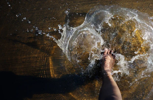 Adamın yalın ayak yağmurdan sonra boş yoldaki cam su birikintisine atlıyor. Kristal berrak su yüksek hızlı kepenk ve seçici odak ile sıçrar.