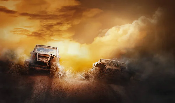 Off-road yarışmasında çamur çukurundan çıkan iki off-road aracı.
