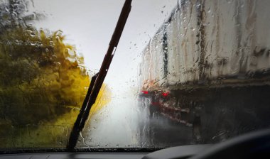 Sürücü, yağmur fırtınası sırasında yoldaki kötü hava koşulları, seçici odak ve renk tonuyla ön cam manzarası.