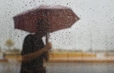 Blurry of the old man with umbrella during hard rainfall/Dramatic scene of rainy season in Southeast Asia).Selective focus and shallow depth of field composition.