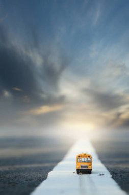 Yellow school bus toy model on country road.Very shallow depth of field composition.