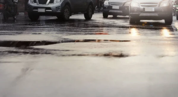 Şiddetli yağmurdan sonra ıslak sokaktaki araba. Asfalt seviyesinden ve seçici odak noktasından görüş.