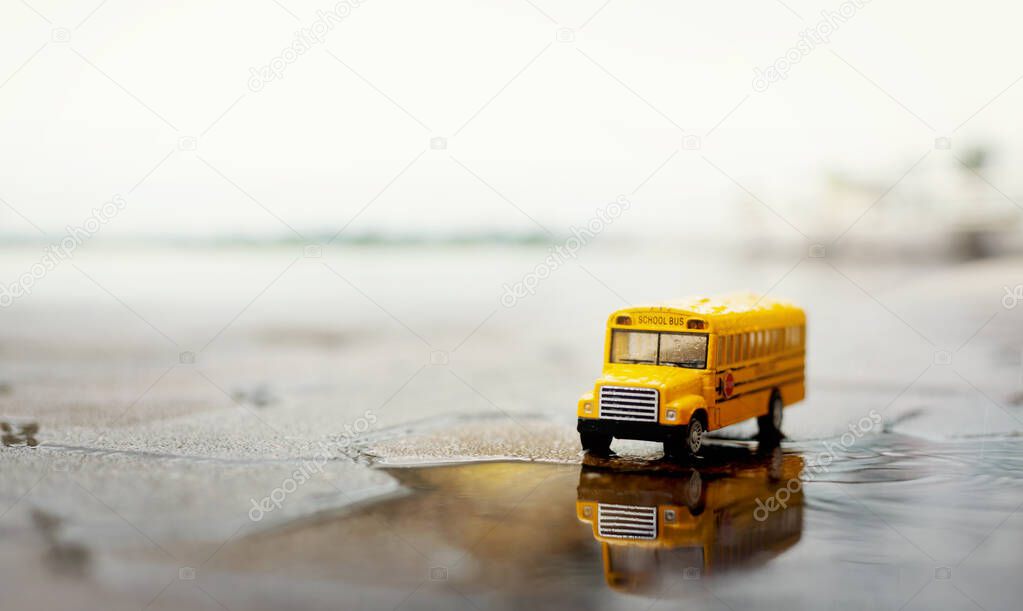 Yellow school bus (toy model) during hard rain fall in city,low angle view and shallow depth of field composition.Back to school concept background.