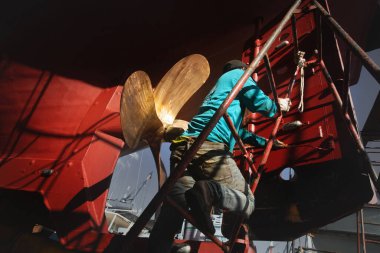 Tersanede geminin yan tarafında boyama yapan işçiler..