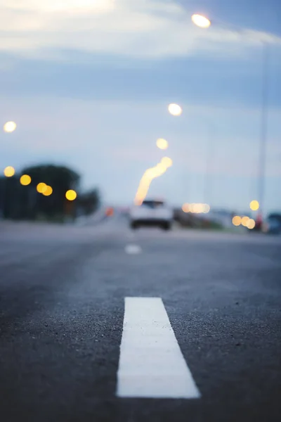 Blurry of car and asphalt road at dusk.Selective focus with very shallow depth of field.Travel and transportation concept background.