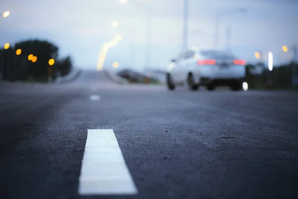 Blurry of car and asphalt road at dusk.Selective focus with very shallow depth of field.Travel and transportation concept background.