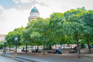 Berlin - 26 Ağustos 2017; Berlin 'de Jandarma şehir meydanındaki ağaçların altında dinlenen çift, sigara içiyor, cep telefonuna bakıyor ve iletişim kuruyor..