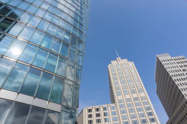 Potsdamer Platz Berlin 'de birleşen caddeden gökyüzüne doğru çeşitli dış cephe malzemelerine sahip yüksek binalar yükseliyor..