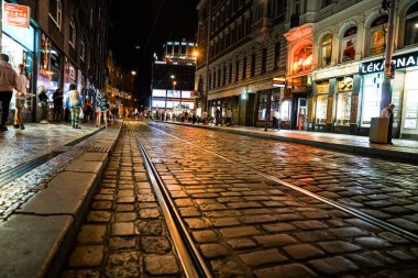 Prag Çek Cumhuriyeti - 30 Ağustos 2017; Kentte gece yarısı kaldırımlardan ve tramvay hatlarından parlayan ışıklar ve aydınlık dükkan pencerelerinden geçen insanlarla.