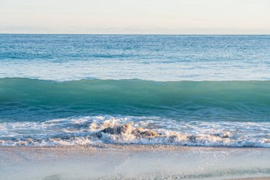 Yeni Zelanda, Tauranga 'daki Maunganui Dağı' nın arka planında dalgalar kırılıyor..