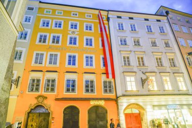 Salzburg Avusturya - 6 Eylül 2017: Motzart 'ın evi de dahil olmak üzere çok katlı apartmanlar tarafından eski kasabalarda ve turistlerin uğradığı uzun süreli gece sahnelerinde insanlar hareket halinde bulanıklaştı