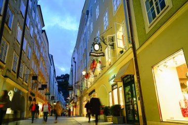 Salzburg Avusturya - 6 Eylül 2017: Yüksek perakende satış ve turist dükkanlarının bulunduğu eski şehir ilçesinde insanlar uzun gece görüntülerinde sokakta yürürken hareket halinde bulanıklaştı.
