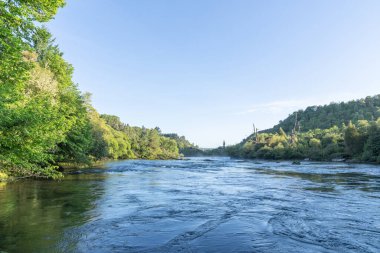 Güneş, Huka Şelalesi, Taupo, Yeni Zelanda yakınlarındaki Waikato Nehri 'nin üzerinden yükselirken hafif bir sis bulutu oluşur..