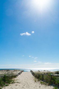 Kumsalın yukarısında gökyüzünde güneş yüksekte ve suya dikey bileşim içinde erişim yolu.