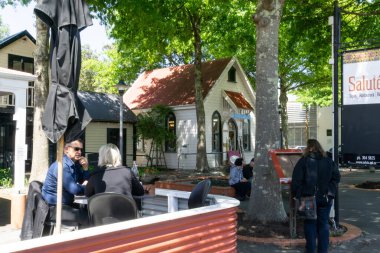 GREYTOWN, NEW ZEALAND - 2 Kasım 2018; İnsanlar 1 sokak sahnesinde ağaçların altında, küçük kasabanın geleneksel mimarisi ile açık kafede oturuyorlardı.