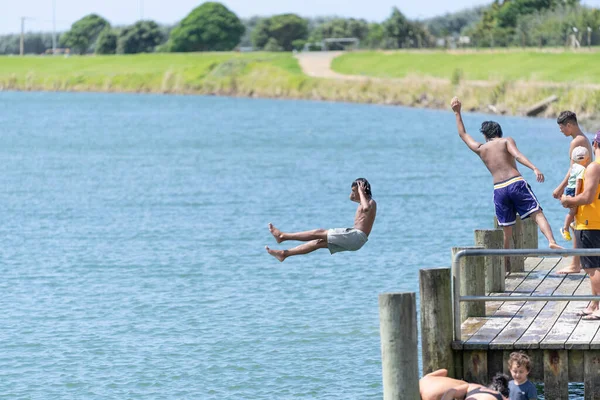 Opotiki Yeni Zelanda - 30 Ocak 2022; Gençler Otara Nehri 'ne atlayıp yaz eğlencesinin tadını çıkarıyorlar