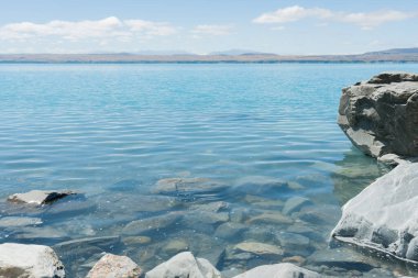 Güney NZ, Canterbury 'deki Pukaki Gölü' nün kayalık kıyı şeridi turkuaz suyu..