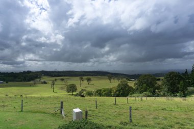 Güneş, toplanan bulutları delip yeşil otlakları ve aşağıdaki şeytanları vurguluyor.