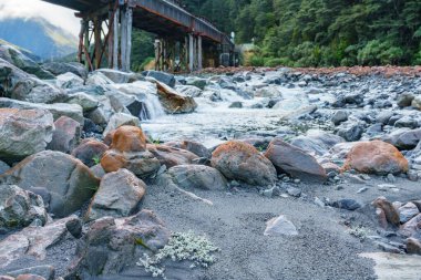Ön planda nehir yatağı ve Bealey Nehri 'ndeki demiryolu köprüsünün altındaki Güney Adası Yeni Zelanda' daki Arthurs Geçidi 'ne odaklanılıyor..