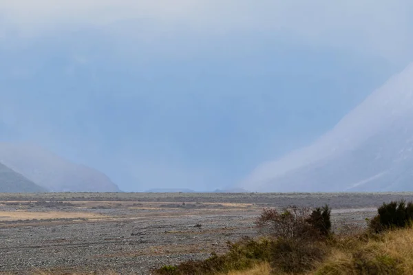 Diminishing perspective of mountain ridges fading into mist around flat valley landscape.