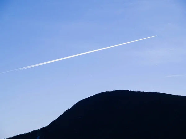 White Jet Stream Clear Blue Sky Back Lit Silhouette Hill — Stockfoto