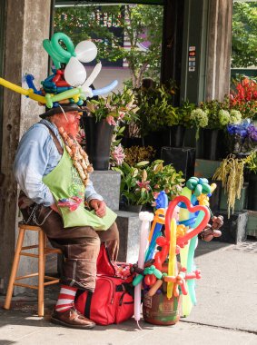 Seattle USA - July 20 2008; Pike place Balloon man sitting outside looking bored surrounded by balloons in various shapes
