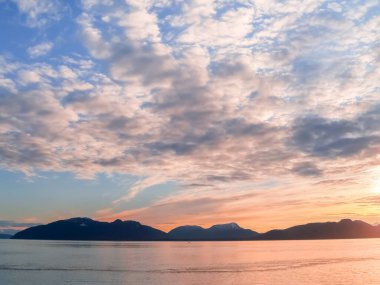 Sunset and silhouette distant hills and land in Alaskan travel image.