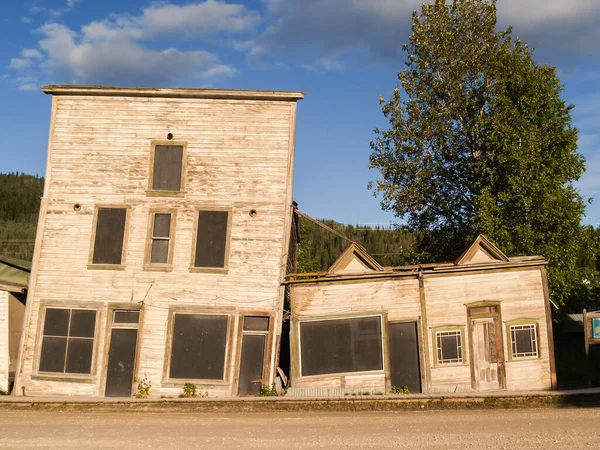 Old wooden buildings collapsing as perma-frost ground sinks underneath a long term effect of changing climatic conditions.