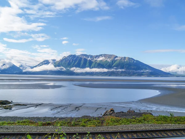 Mountains with low cloud surrounding the bays and railway track in foreground of coastal Kenai Peninsula, Alaska.