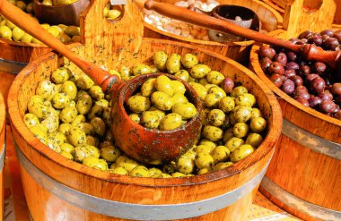 Fıçılar dolusu yeşil ve kırmızı zeytin yağlı bardaklar ve pazarda bitkiler.