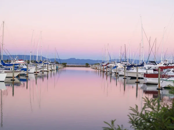 美丽的粉色和蓝色映衬在平静的水面上 船泊在码头上 — 图库照片