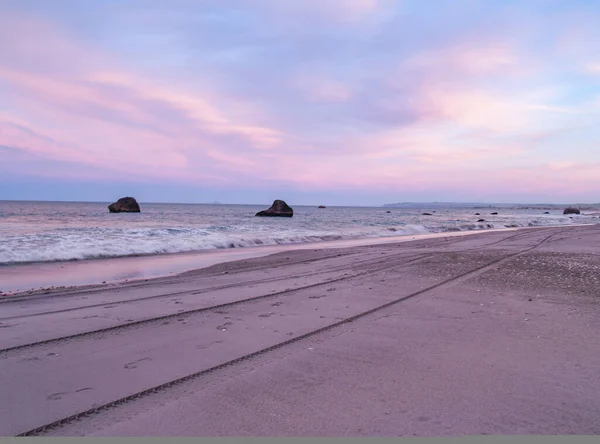 在潮湿的沙滩上反射出夕阳西下的色彩 并在丰饶的海岸线上勾勒出轮廓 — 图库照片