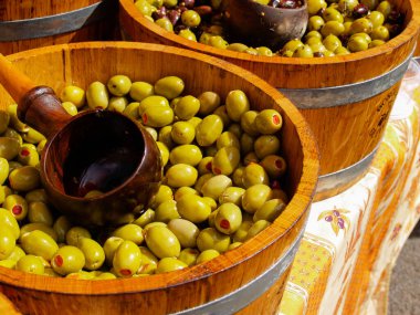 Fıçılar dolusu yeşil ve kırmızı zeytin yağlı bardaklar ve pazarda bitkiler.