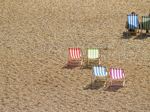 Deck chairs on Brighton Beach characteristic orange pebbles view below