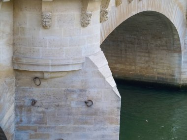 Fransa, Paris 'te taş köprünün altından akan küçük heykel yüzlü nehir..