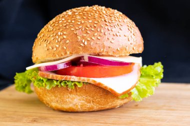 Köfteli burger, domates, soğanlı, siyah arka planda.