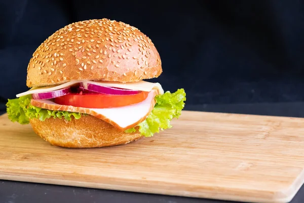 La hamburguesa con el queso de carne la cebolla de tomate en la tabla sobre el fondo negro el espacio de copia — Foto de Stock