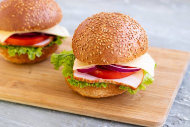 İki hamburger, domates ve tahta tahtada peynir salatası..