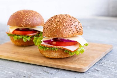 İki hamburger, domates ve tahta tahtada peynir salatası..