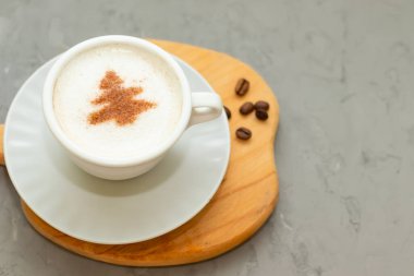 Tarçın desenli kapuçino kahve fincanı, çimento arka planda noel içeceği.