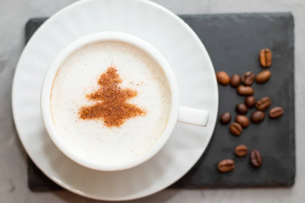 Biały kubek kawy cappuccino na betonowym tle obok ziaren kawy — Zdjęcie stockowe