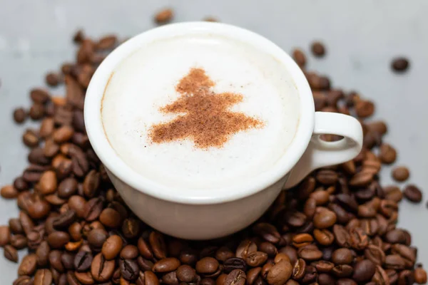 Біла чашка кавового капучино на бетонному фоні поруч з кавовими зернами — стокове фото