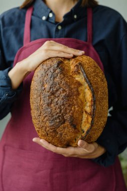 Mayasız ekşi ekmek. Avrupalı güzel bir fırıncı elinde ekmek tutuyor.