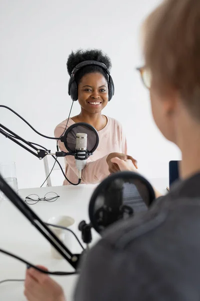 record a podcast and create audio content. An African American woman plays the ukulele in a recording studio or on the radio