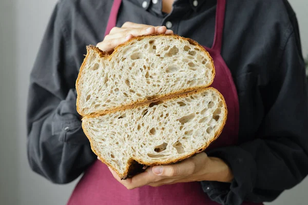 yeast-free sourdough bread. a beautiful European woman baker holds bread in her hands