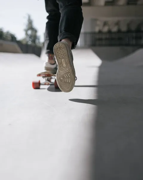 Uma patinadora europeia com cabelo ruivo está montando um skate em um skate. uma mulher em roupas pretas e um skate ou um longboard está envolvida em esportes ativos — Fotografia de Stock